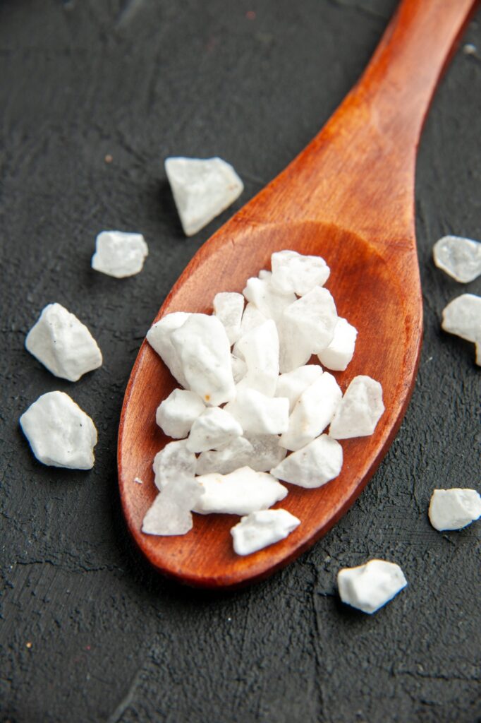 Bottom view sea salt on wooden spoon on black surface