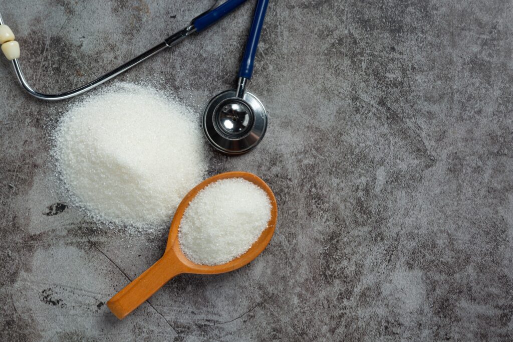 sugar in wooden bowl and stethoscope on dark background