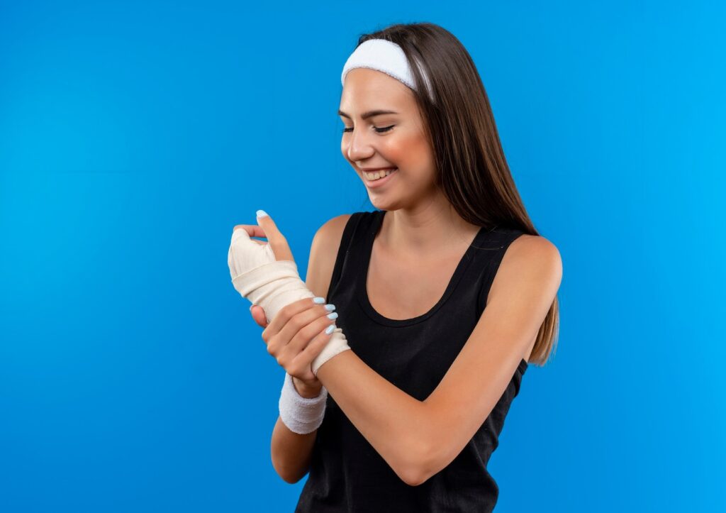 Smiling young girl wearing headband and wristband holding looking at her injured wrist